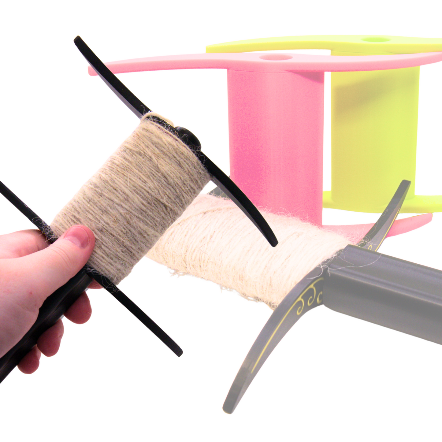 hand holding a black druga sloak spindle with a pink and lime green reel in the background to demonstrate the reel's replacability