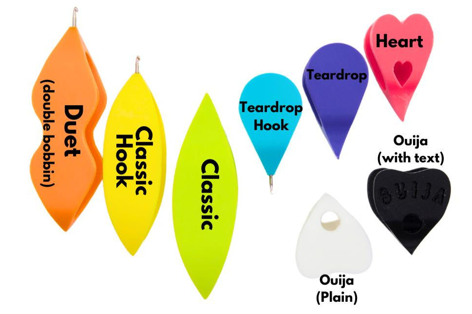 an assortment of colourful plastic tatting shuttles labelled with their names. The types of shuttle are duet (double bobbin), classic hook, classic, teardrop hook, teardrop, heart, ouija (plain) and ouija (with text)