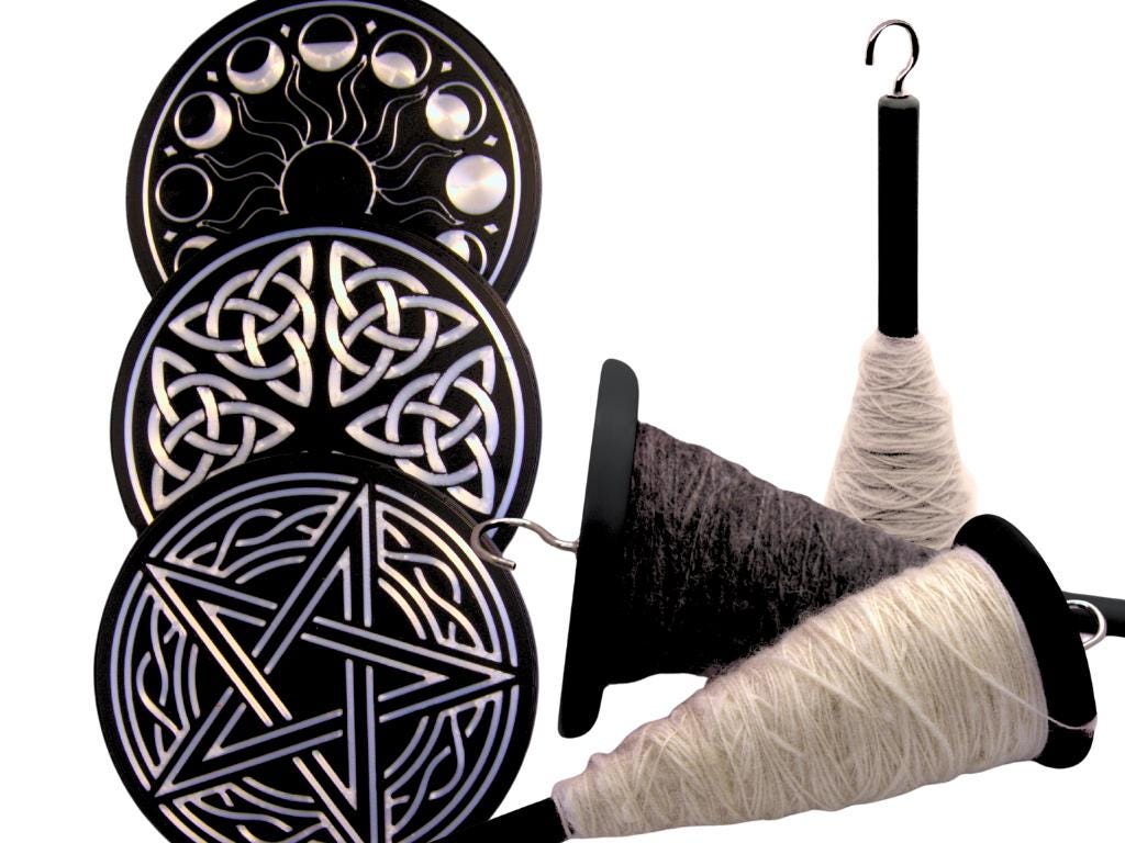 Embellished drop spindle with yarn and Celtic knot designs on a white background